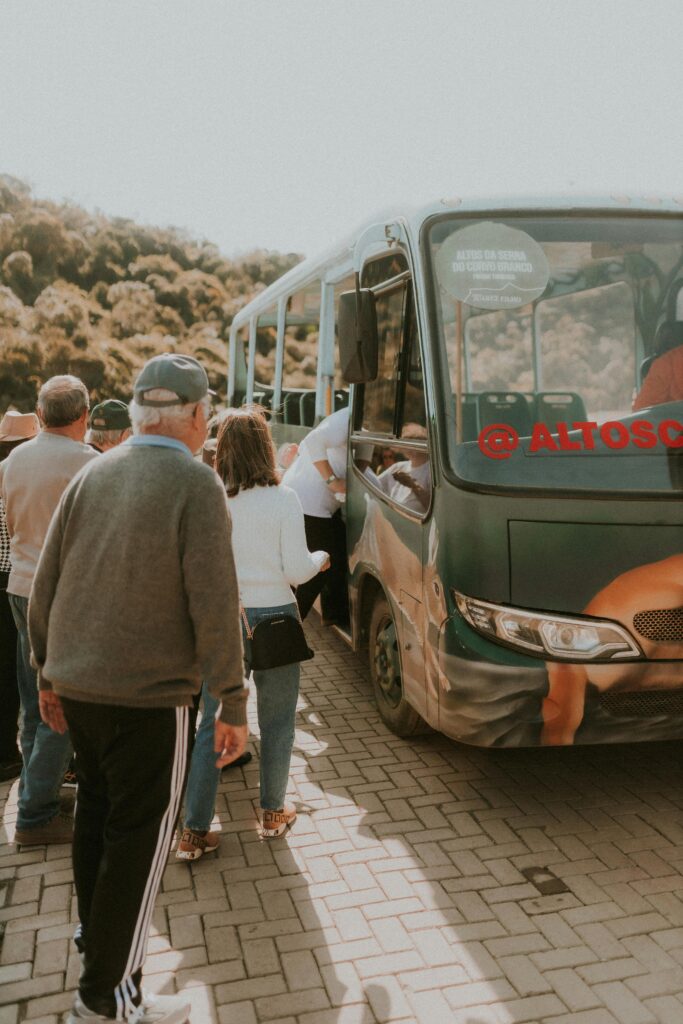 pexels-photo-27757761-27757761 Group of people boarding a bus surrounded by nature, showcasing travel and transportation.