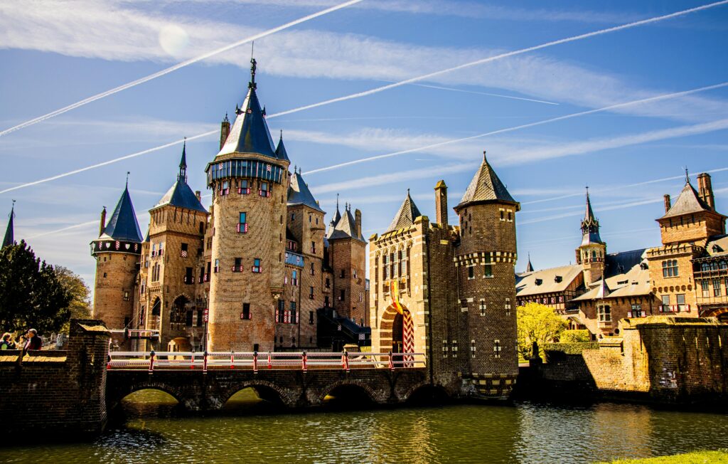 Majestic castle in Utrecht with a bright blue sky and water reflection.