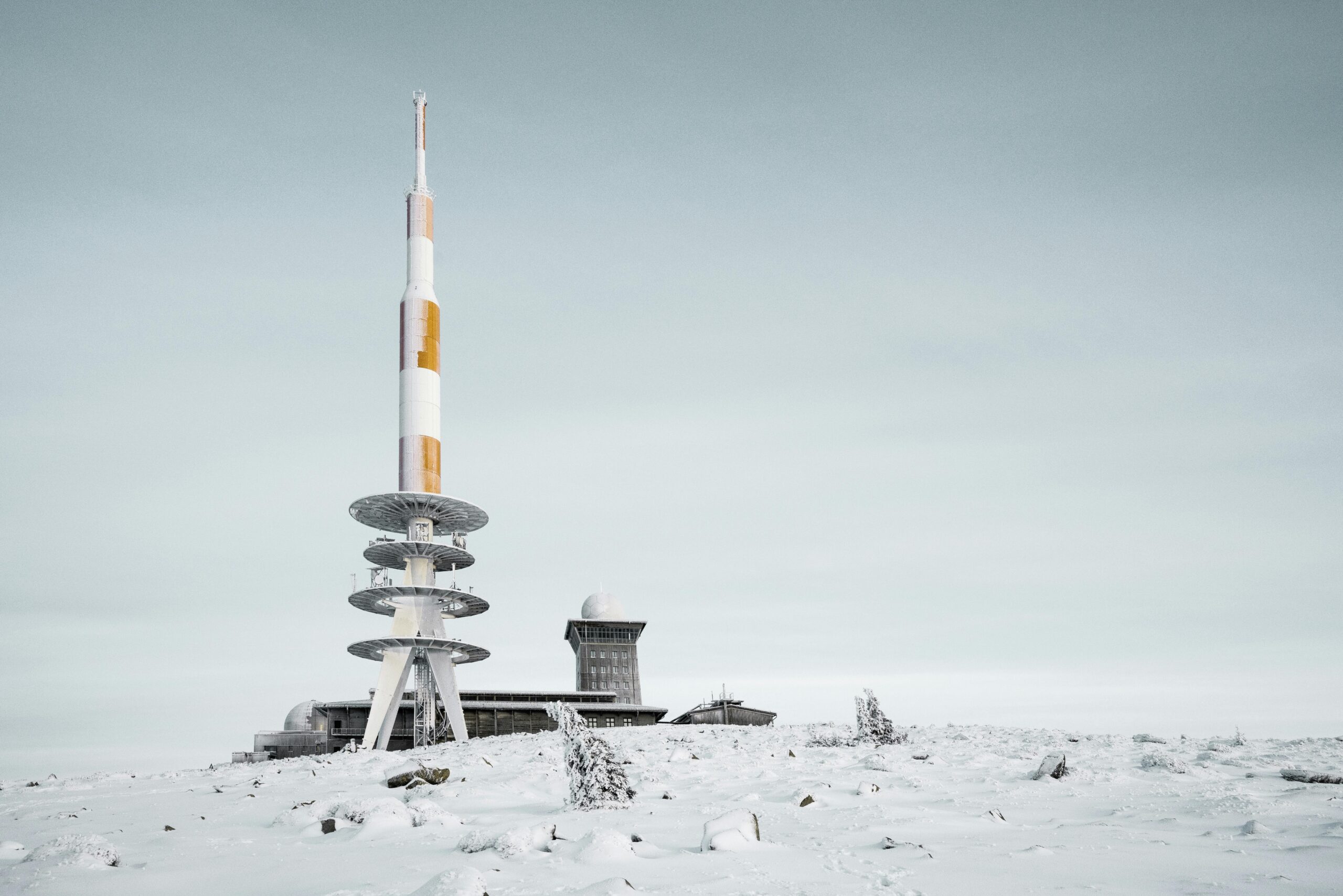 Capture of the snowy Brocken transmitter tower in Harz, Germany, against a clear winter sky.